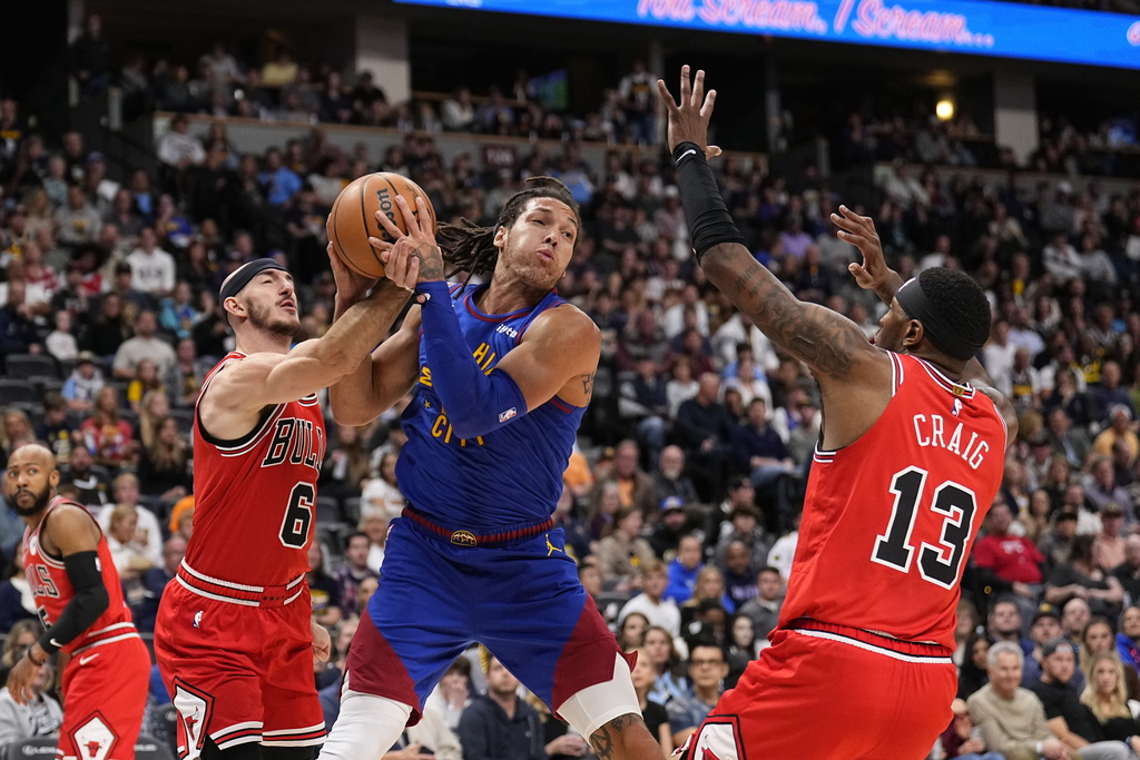 Denver Nuggets forward Aaron Gordon, center, is pressured by Chicago Bulls guard Alex Caruso...