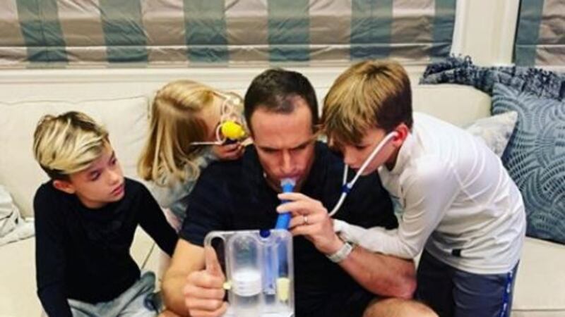 Saints QB Drew Brees, surrounded by his children, uses a breathing device to assist with a...